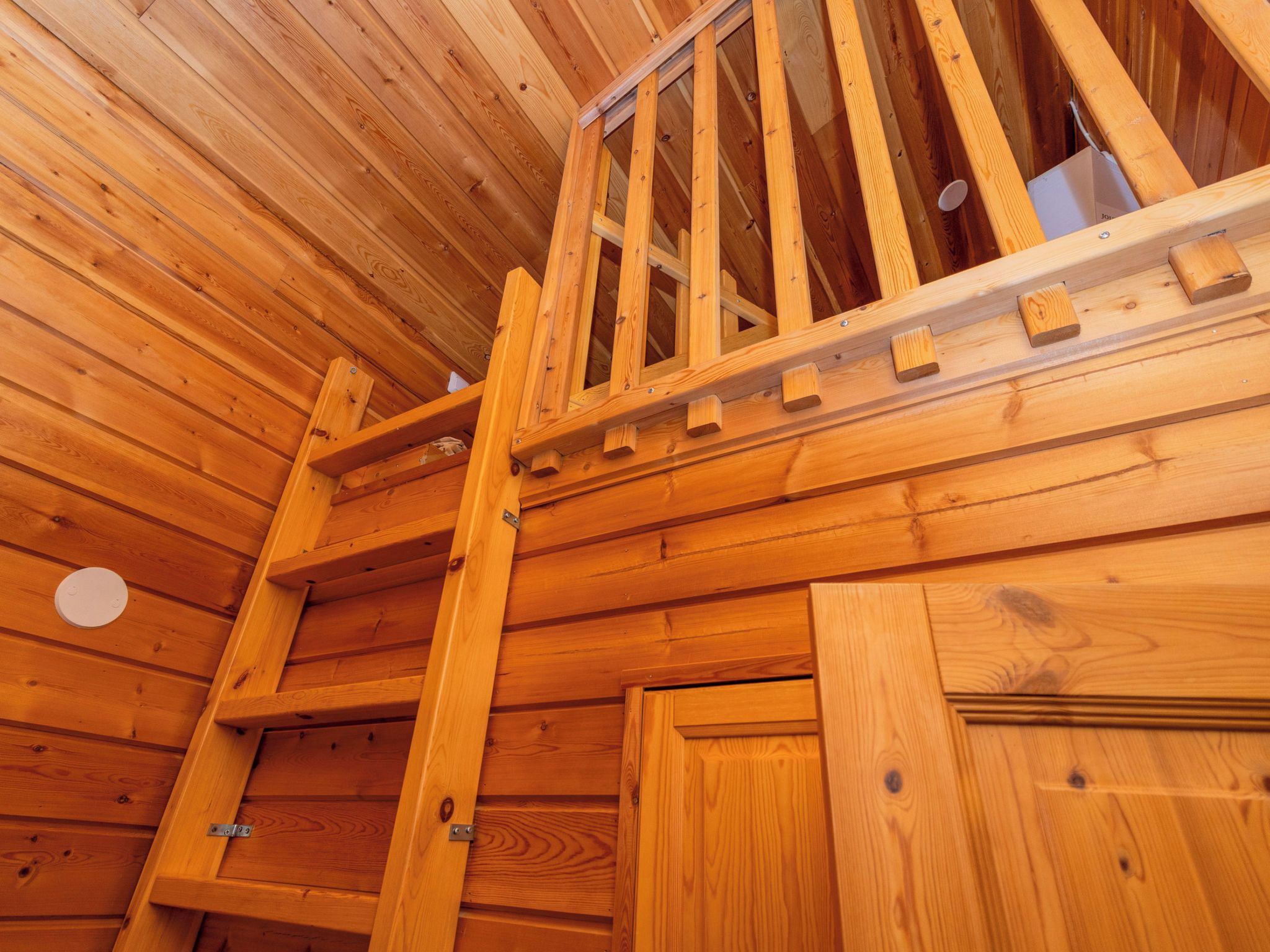 Een houten interieur met een trap naar een vide.