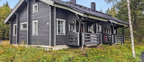 Eine zweistöckige Holzhütte mit Veranda, umgeben von dichter Natur.