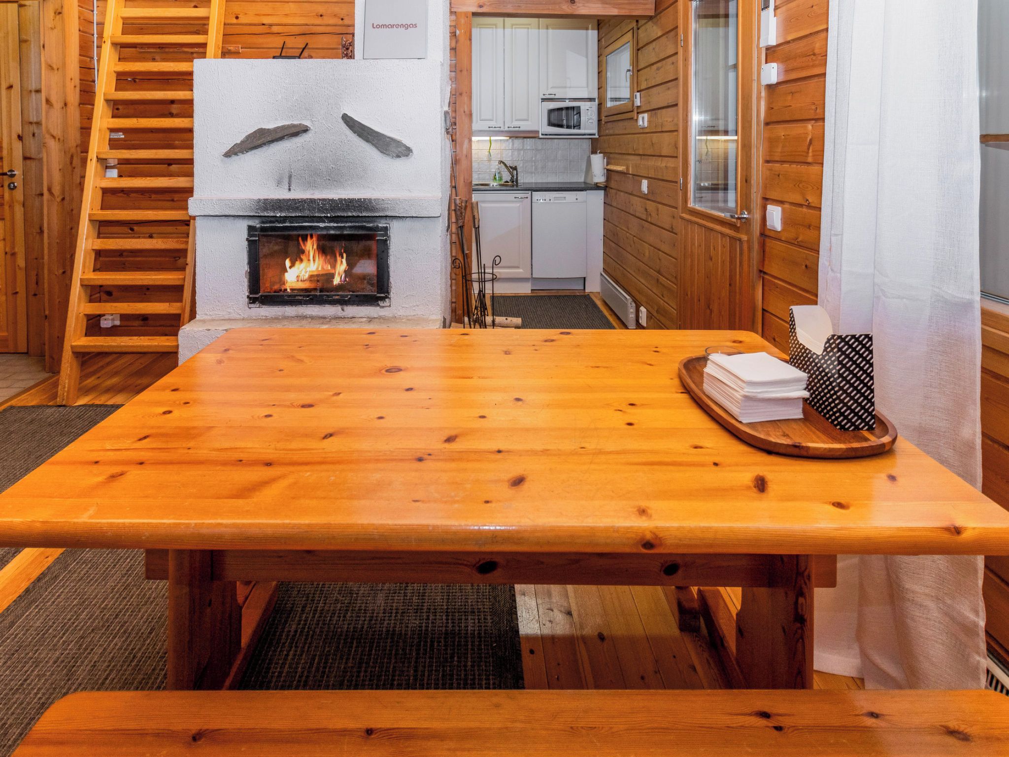 Een houten interieur met een open haard, een keukenhoek en een eettafel.