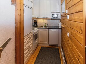 A compact kitchen with white cabinets, a microwave, a coffee maker, and a dishwasher.