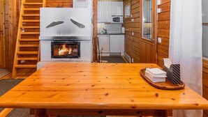 Un interior de madera con chimenea, una zona de cocina y una mesa de comedor.