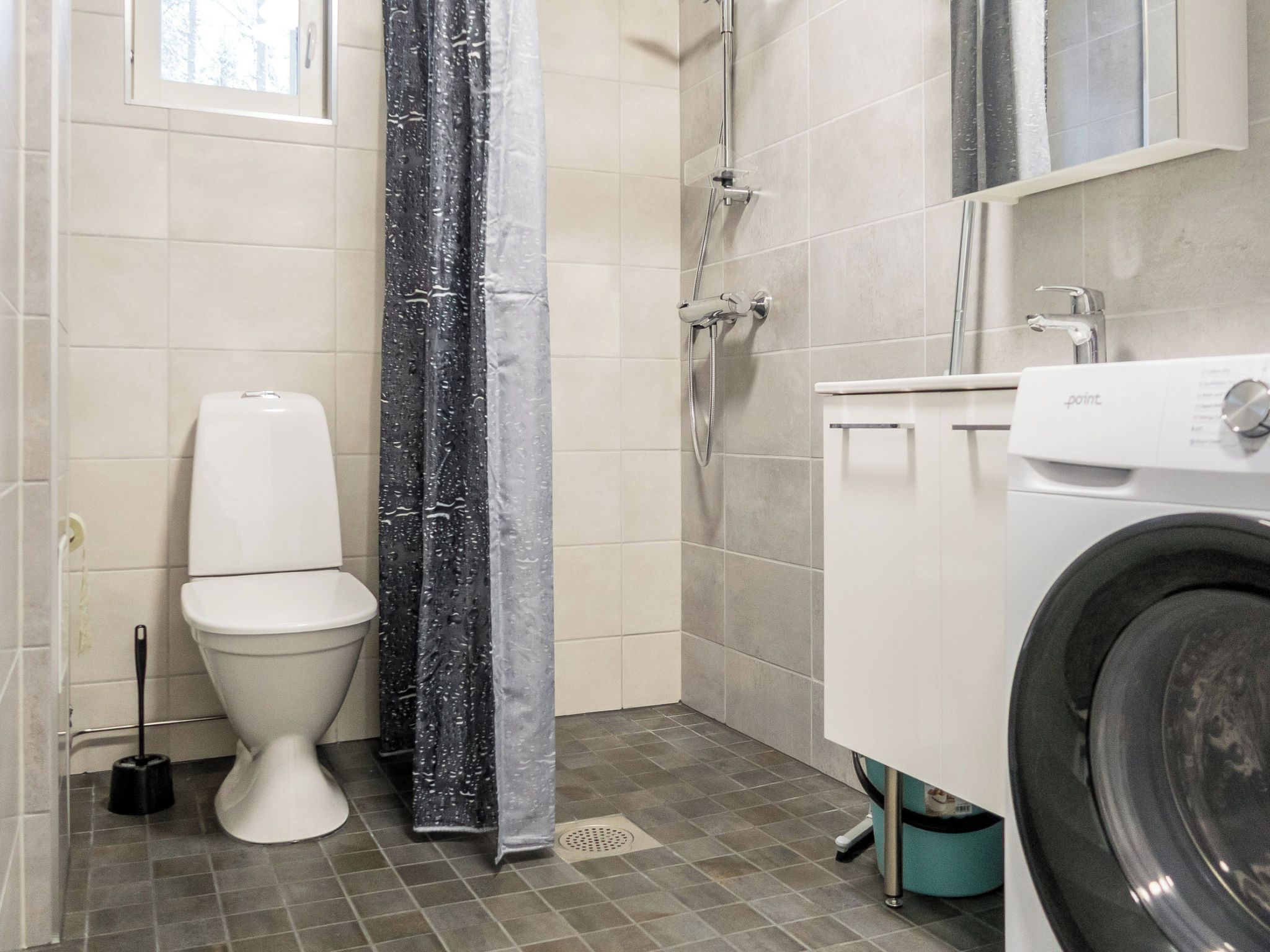 A bathroom with a toilet, shower, and washing machine.