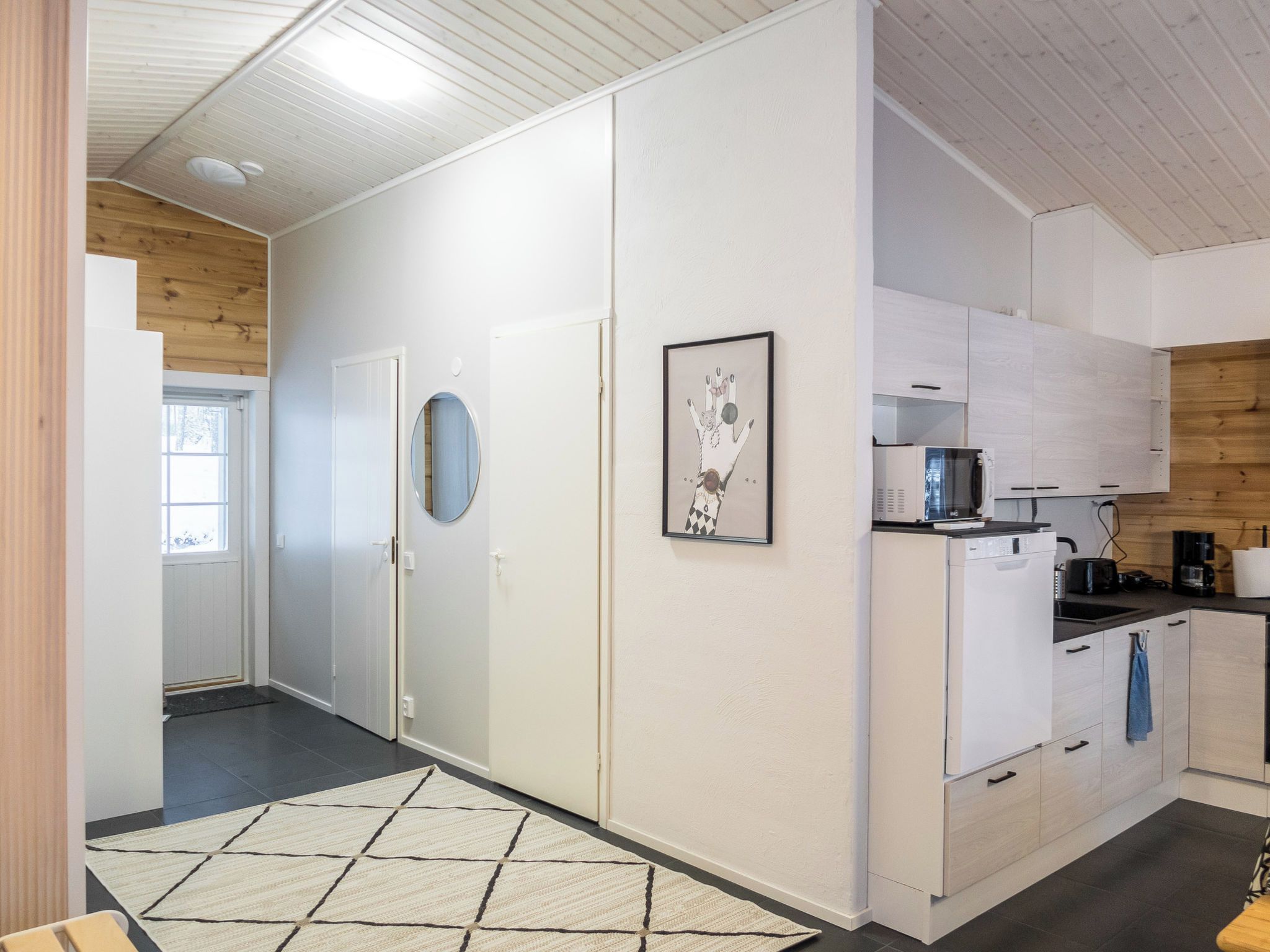 A modern kitchen with white cabinets, a microwave, and a coffee machine.