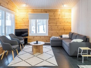 A modern living room with a sectional sofa, two armchairs, a coffee table, and a television. - Vacation home Kianta by Interhome (Sotkamo)