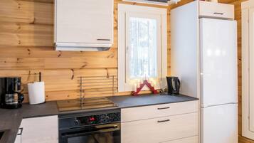 Une cuisine moderne avec des murs en bois, un fourneau, un réfrigérateur et une fenêtre donnant sur les arbres.