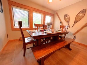 A dining room with a wooden table and chairs, a bench, and a window with blinds. - Walk to Main St. • Near Snowflake Lift • Hot Tubs+Pool (Breckenridge)