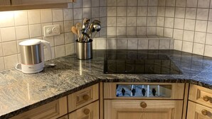A kitchen with wooden cabinets, a granite countertop, a stainless steel kettle, and a built-in stove. - Alpenglühn by Interhome (Adelboden)