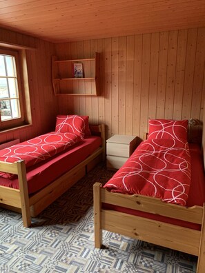A small, cozy room with two wooden bunk beds, a small wooden nightstand, and a shelf with a picture. - Alpenglühn by Interhome (Adelboden)