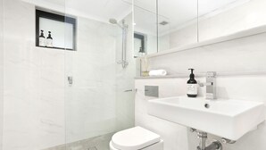 Une salle de bain moderne avec un lavabo blanc, des toilettes et un espace douche.