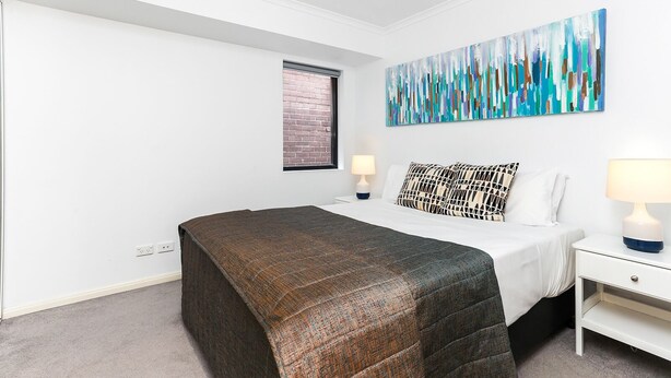 Una camera da letto moderna con un letto, comodini, una finestra e un grande quadro astratto.