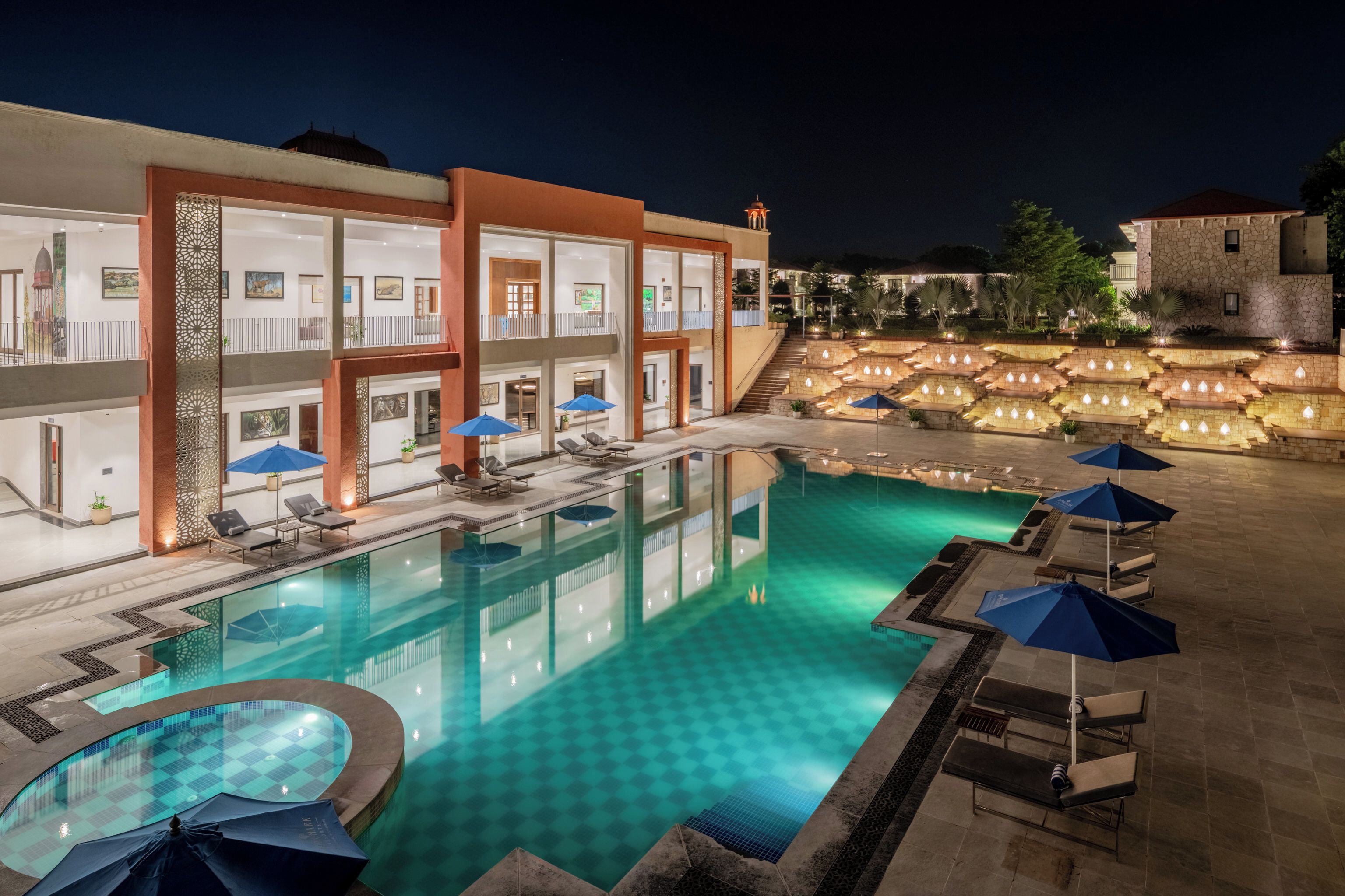 Un hotel su più livelli con piscina, lettini prendisole e una scala che conduce a una terrazza.