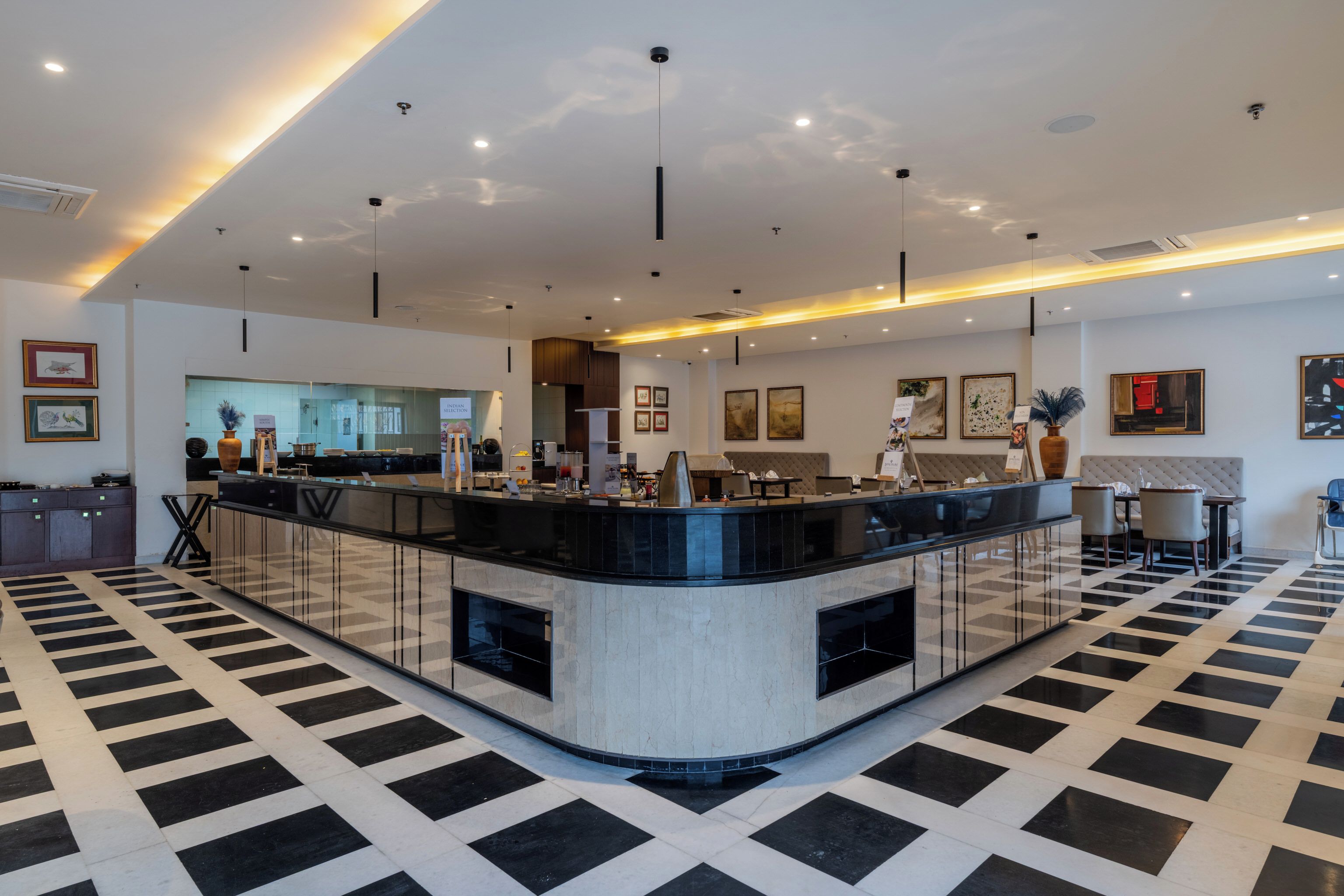 A modern hotel lobby with a central reception desk, seating area, and artwork on the walls.