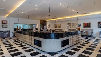 A modern hotel lobby with a central reception desk, seating area, and artwork on the walls.
