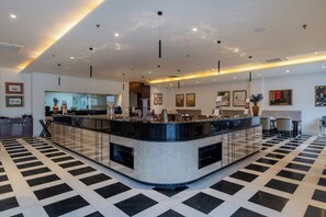A modern hotel lobby with a central reception desk, seating area, and artwork on the walls. - Bookmark Resorts - Jogi Mahal, Ranthambore (Sawai Madhopur)
