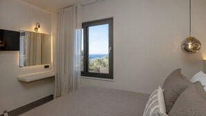 Ein Schlafzimmer mit Bett, Fenster mit Blick, Wand-Fernseher und Pendelleuchte.