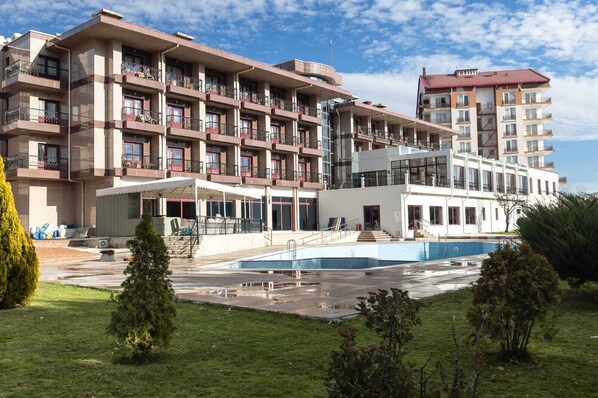 Un hotel de varios pisos con balcones, piscina y un área exterior techada.