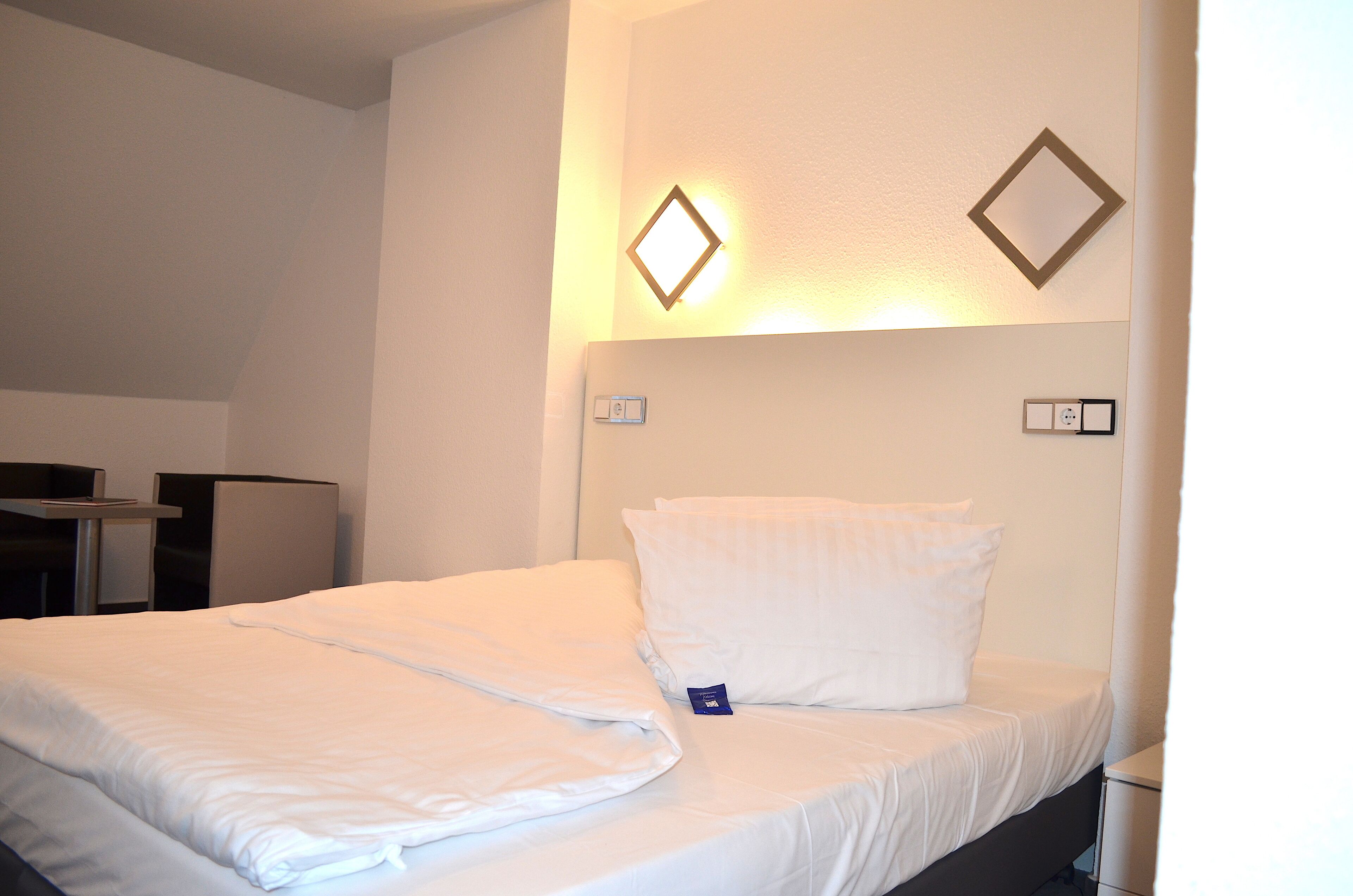 A hotel room with a neatly made bed, a desk, and a chair.