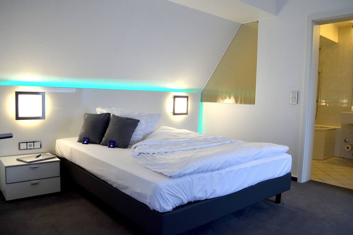 A modern bedroom with a bed, nightstands, and wall-mounted lights.