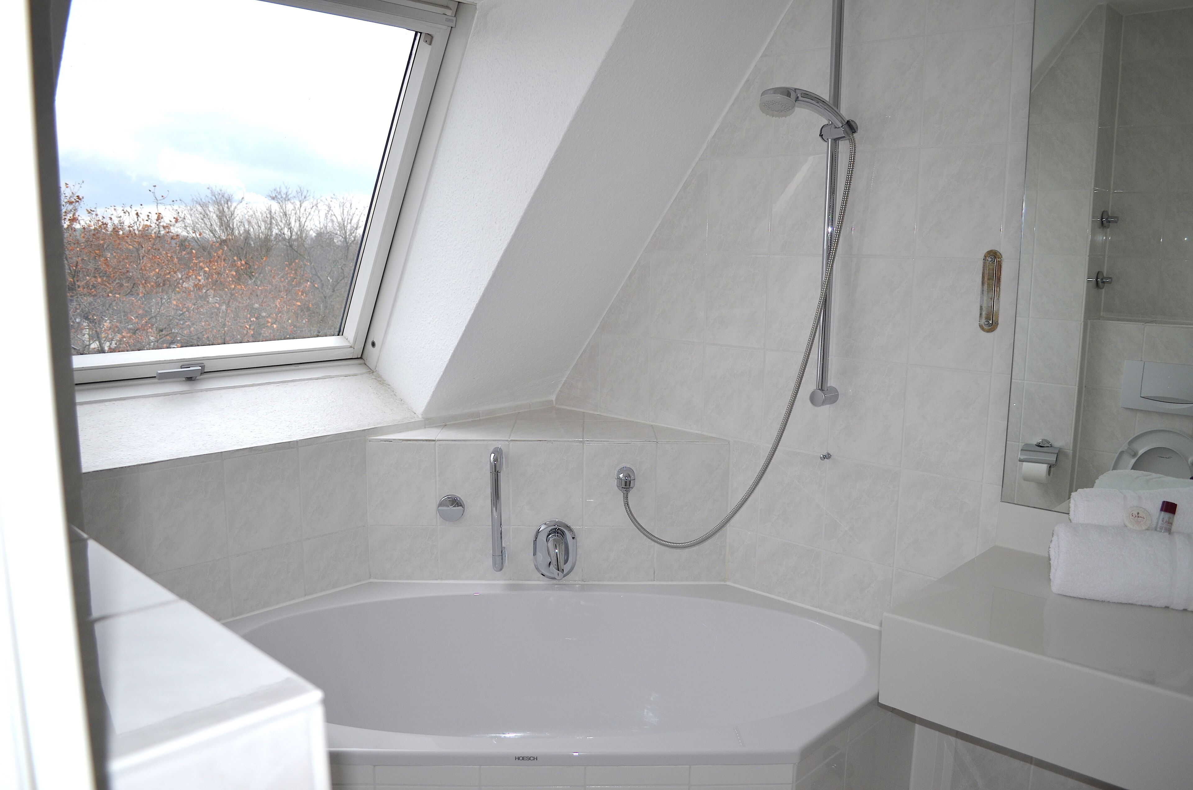 Un baño moderno con una bañera independiente, un cabezal de ducha y un espejo grande.