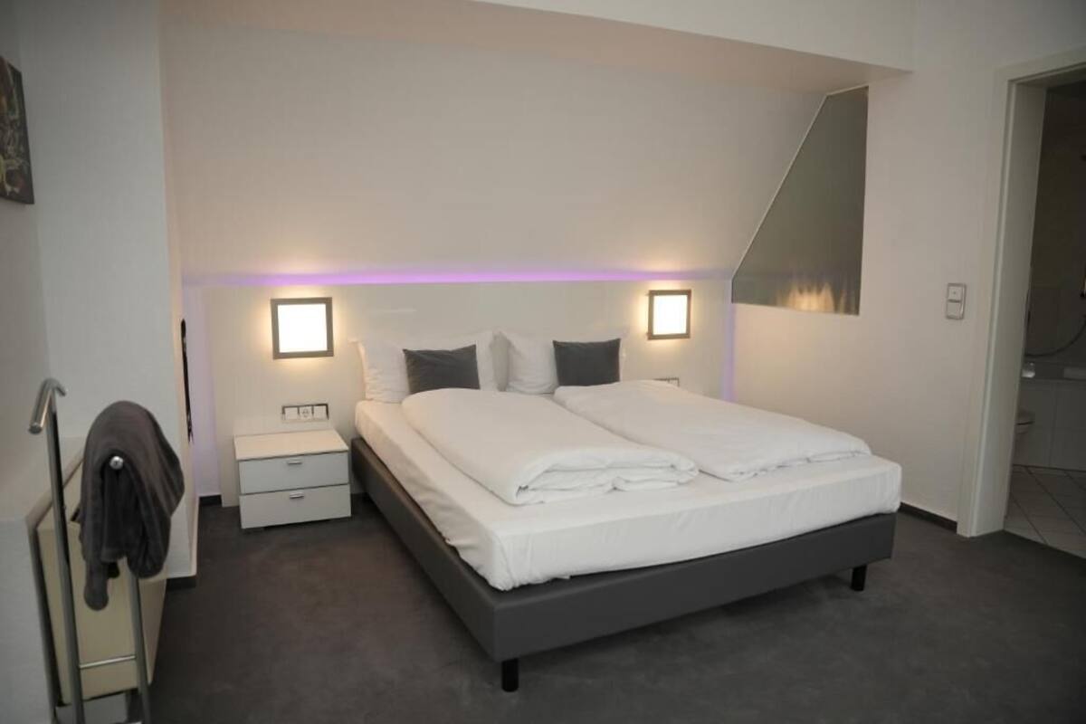 A modern bedroom with a bed, bedside tables, and a mirror.