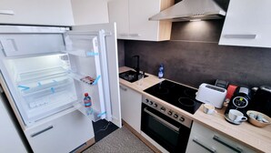 Une cuisine compacte équipée d’un réfrigérateur, d’une cuisinière, d’un four et d’un petit plan de travail sur lequel se trouvent un grille-pain et une machine à café.