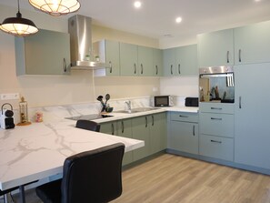 Enjoy cooking in this well-equipped kitchen with a stainless steel range hood, microwave, and ample countertop space.