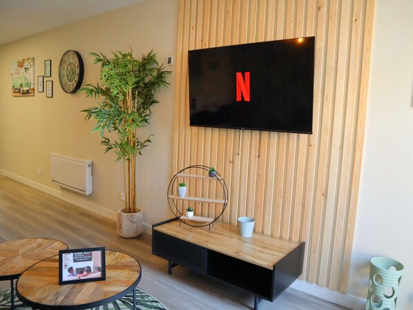 Relax in this stylish living room with a flat-screen TV, bamboo plant, and cozy coffee table.