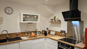 Una cocina moderna con estufa integrada, un lavamanos y un reloj en la pared.