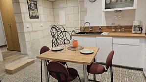 Cocina compacta con una mesa de madera, cuatro sillas, un lavamanos y una cafetera.
