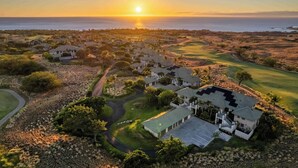 Een golfbaan met huizen en uitzicht op een zonsondergang.