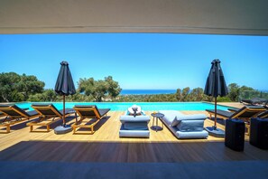 A poolside area with lounge chairs, umbrellas, and a view of the sea. - Villa Nivo: Wellness & Recreation Resort by etouri (Rethymno)