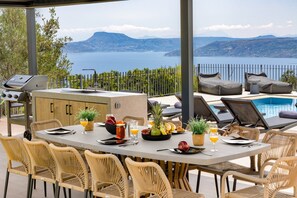 Enjoy al fresco dining with a large table for six, overlooking a serene body of water and distant mountains.