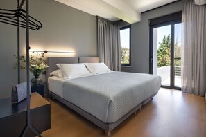 Relax in a spacious room with a large bed, bedside table, and window overlooking lush greenery.