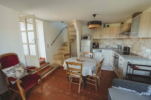 Eine kleine Küche mit Essbereich, einem roten Stuhl und einer Treppe, die zu einer weiteren Ebene führt.