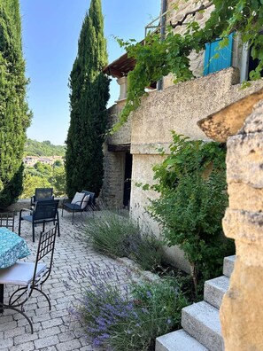 A stone building with a wooden pergola, outdoor seating, and a view of the countryside. - Santoline Holiday Cottage (Niozelles)