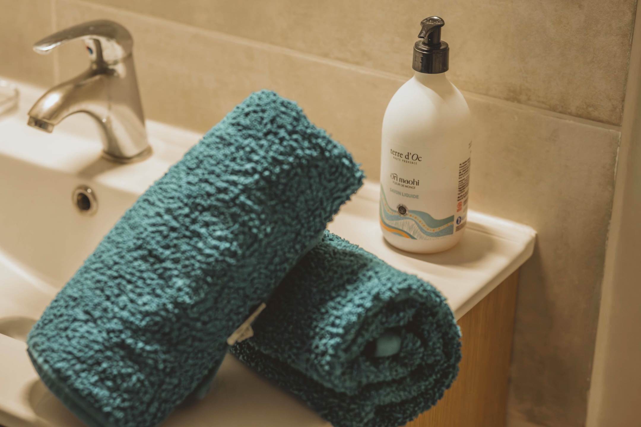 A bathroom sink with a towel and a bottle of hand soap.