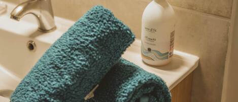 A bathroom sink with a towel and a bottle of hand soap.