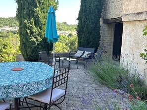 Un patio al aire libre con una mesa redonda, sillas, un sofá y una sombrilla.