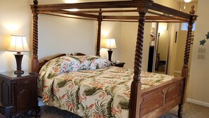 Un letto a baldacchino con copripiumino floreale, due comodini con lampade e una ventola a soffitto.