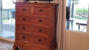 Un comò in legno con un televisore a schermo piatto sopra, adiacente a una porta scorrevole in vetro che si affaccia su un patio esterno.