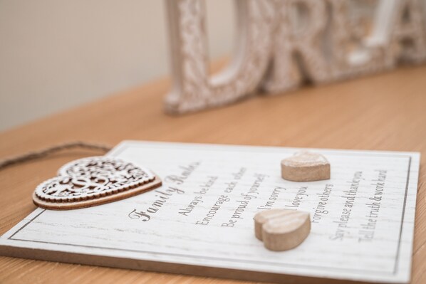 A wooden table with a white sign that reads "Family First" and includes phrases like "Always be kind" and "Encourage each other."