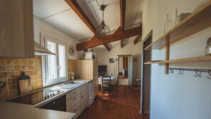 A kitchen with a wooden ceiling, a tiled backsplash, and a dining area with a table and chairs. - Gîte Lavande (Niozelles)