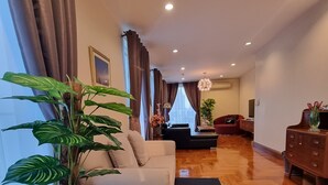 A spacious living room with a sofa, a potted plant, and a wooden floor. - Chez Moi Bangkok Sukhumvit 26 Executive Residence (888) (Klong Toey)