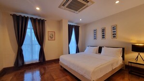 A hotel room with a large bed, wooden flooring, an air conditioning unit, and a bedside lamp. - Chez Moi Bangkok Sukhumvit 26 Executive Residence (888) (Klong Toey)
