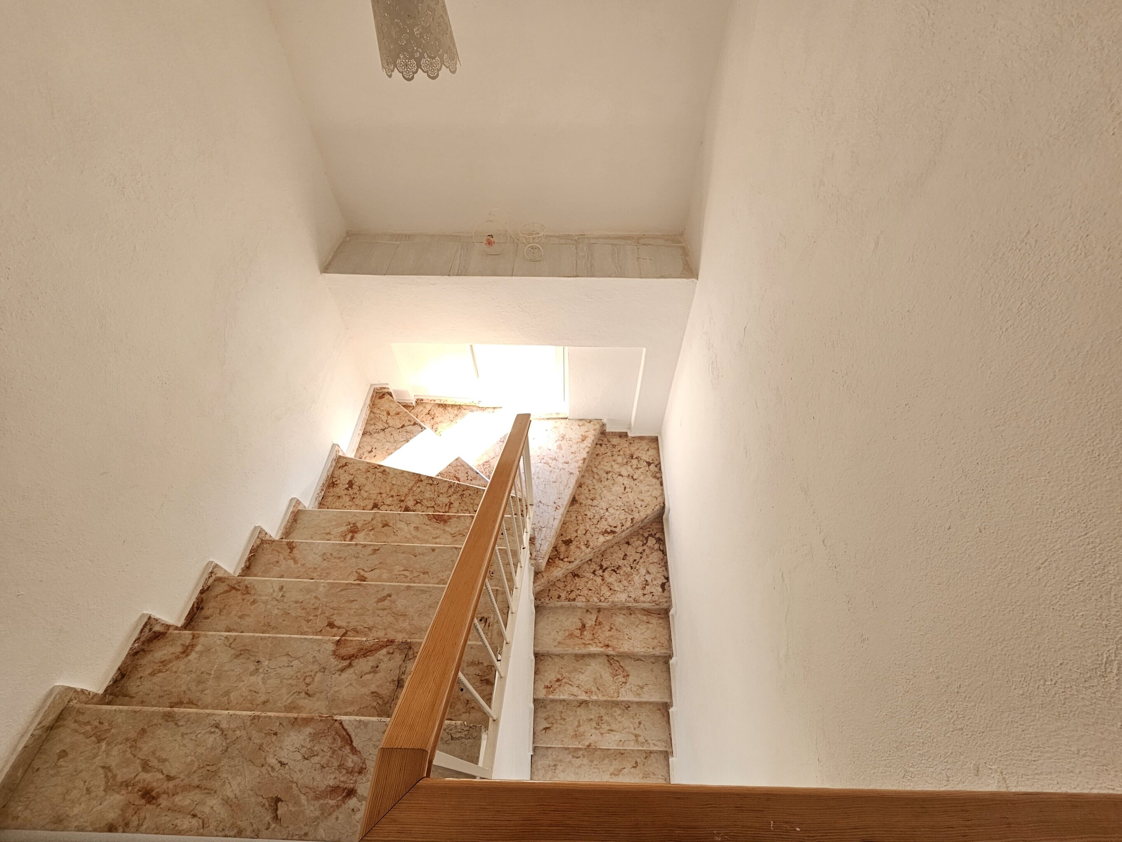 Eine Treppe mit Holzgeländer und weißer Wand.