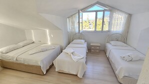 A bedroom with two beds, a small bedside table, and a window with curtains. - Azure Ev Fethiye (Fethiye)
