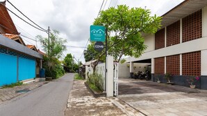 Una casa de huéspedes llamada Matahari en Denpasar, con un área de estacionamiento techada y un letrero que indica que es una entrada COV.