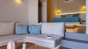 A modern living room with a sofa, a coffee table, and a staircase leading to a bedroom. - Blue Pearl Suite in Tinos  (Tinos Town)