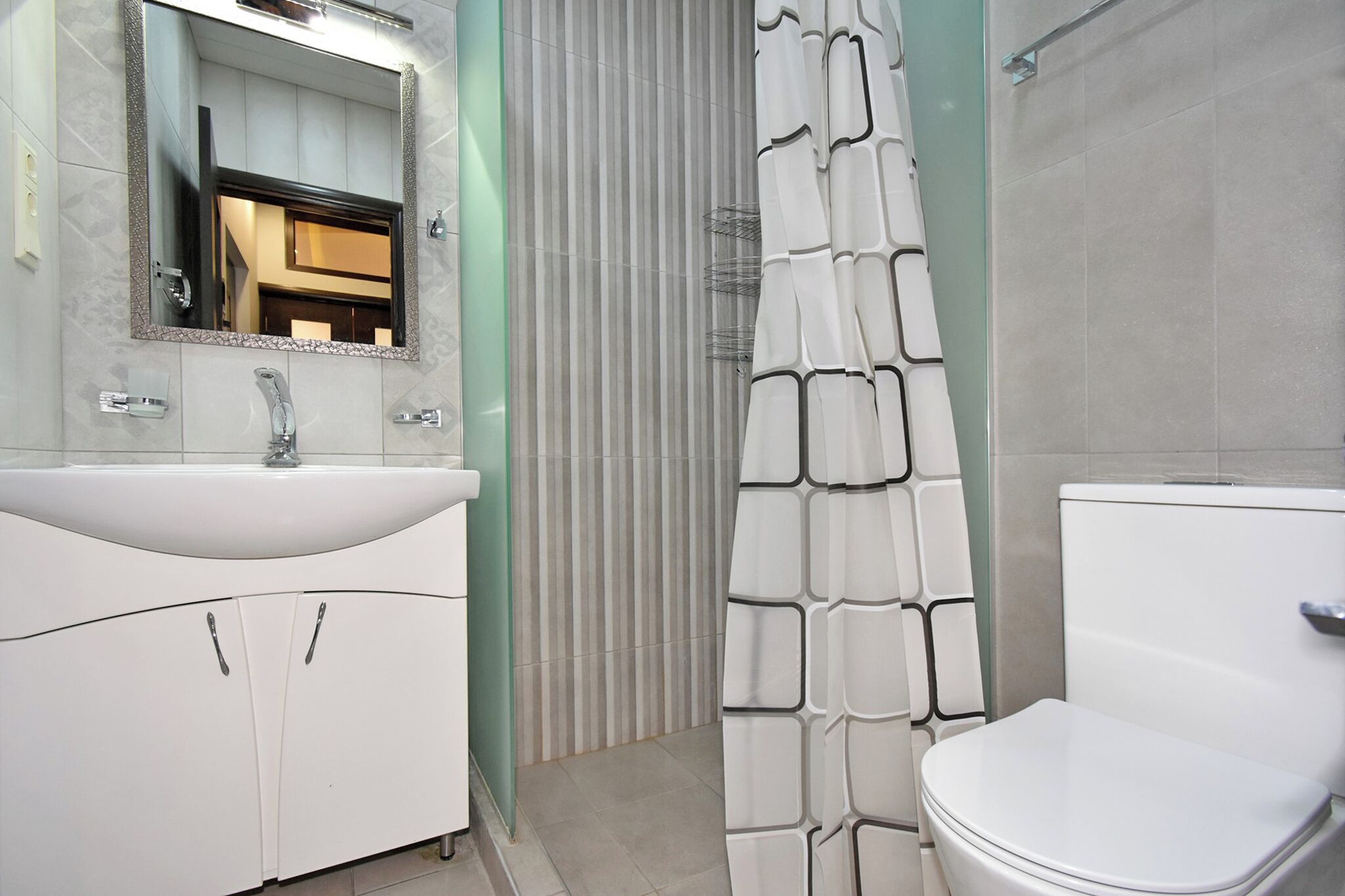 A bathroom with a white sink, mirror, and toilet.