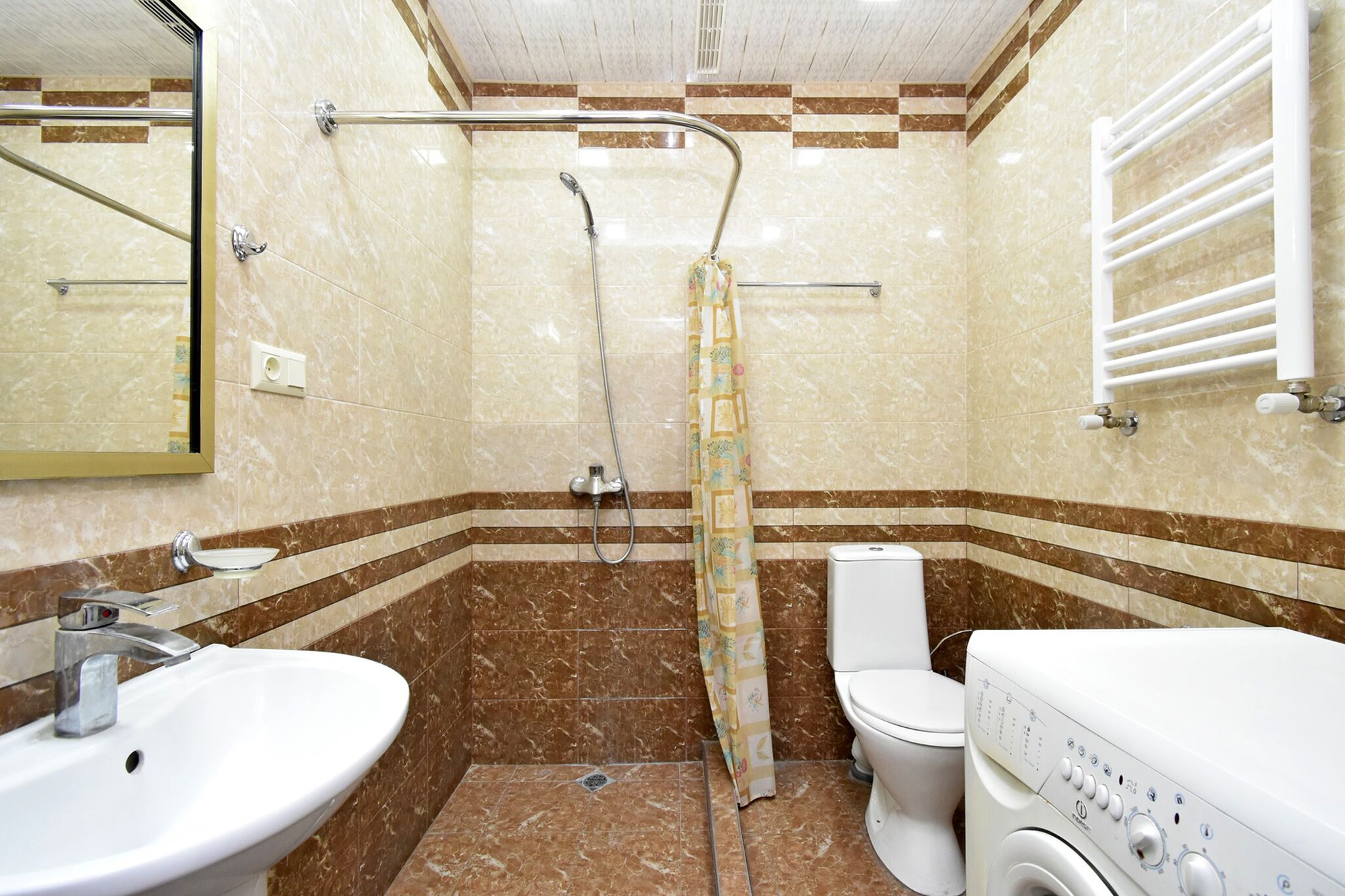 Un baño con lavamanos, inodoro, ducha y lavadora.